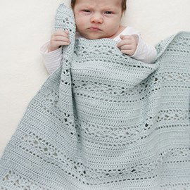 Drops Haakpatroon van een babydeken Sleepy Times. Deze deken is met kantpatroon en wordt gehaakt van het drops garen Safran. Afmetingen: ongeveer 65 x 81 cm.